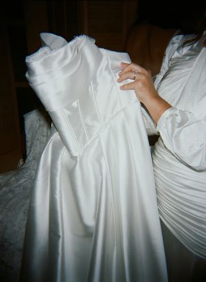 Close-up details of a white satin wedding dress with intricate pleating and fabric texture.