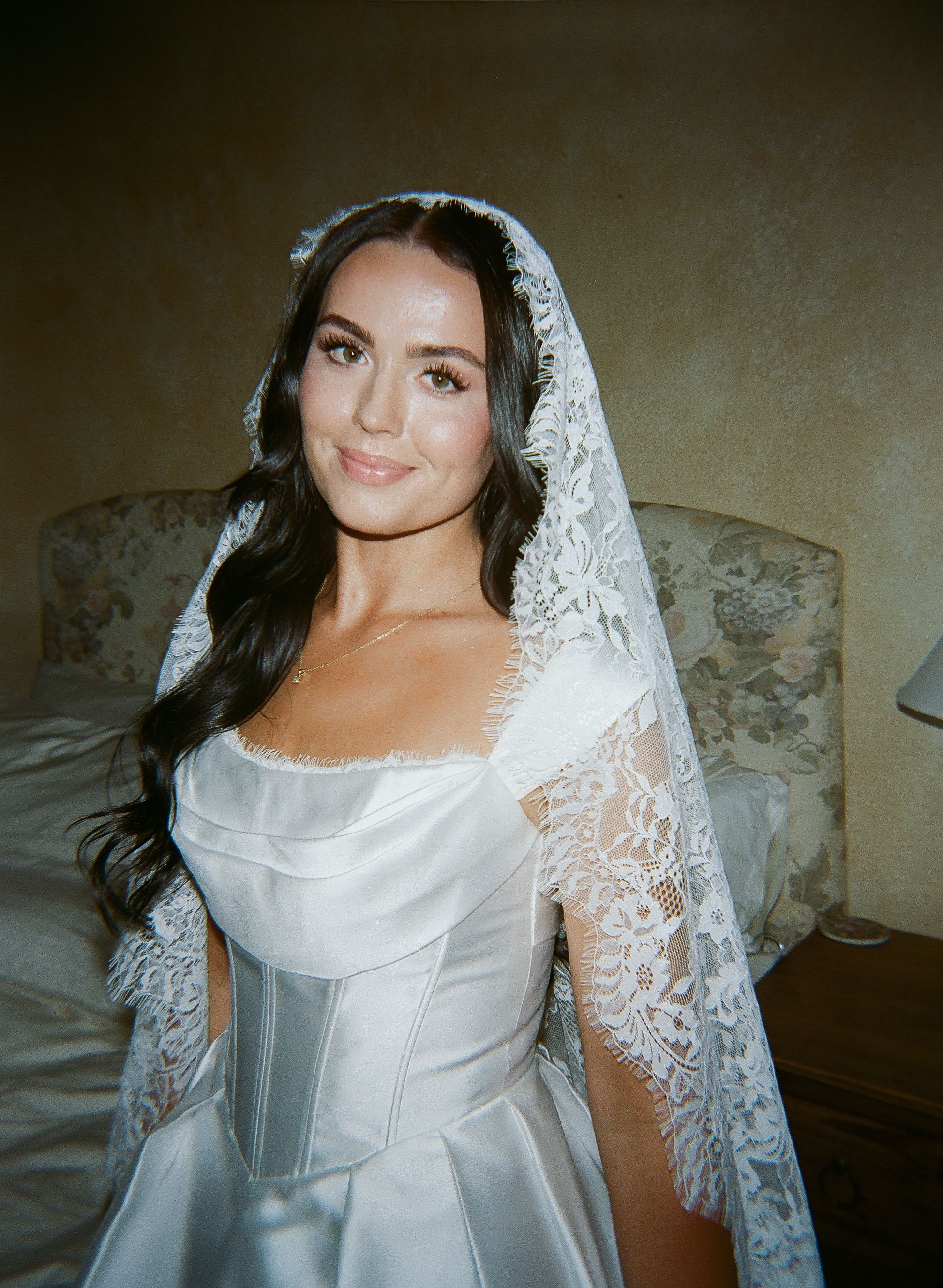 Classic bridal portrait featuring delicate lace veil and structured satin wedding gown.