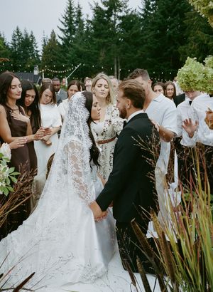 Wedding celebration outdoors with evergreen trees and string lights creating a romantic atmosphere.
