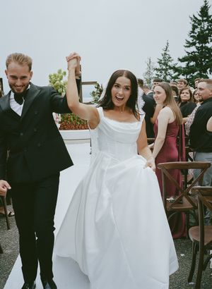 Joyful wedding celebration moment on outdoor pathway with evergreen backdrop.
