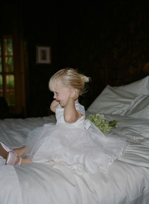 A series of intimate getting-ready moments showing someone in white bridal attire on white bedding.