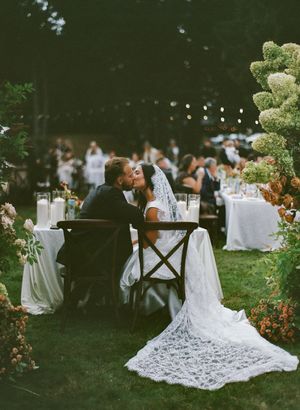 An outdoor wedding reception setup with white tablecloths and lace details in a garden setting.