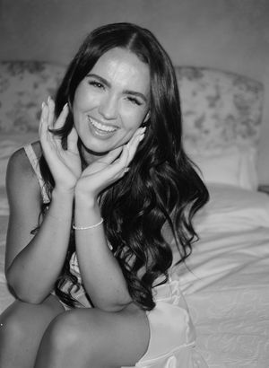 Black and white boudoir photography series showing a woman in white posing on bedding with natural lighting.