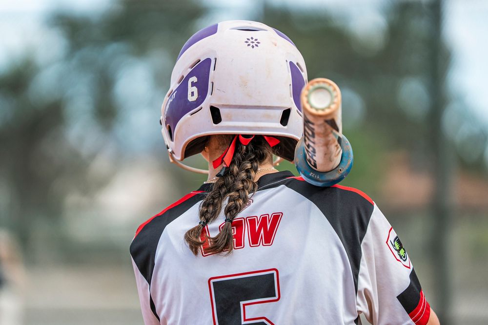 Girls softball player facing away from camera