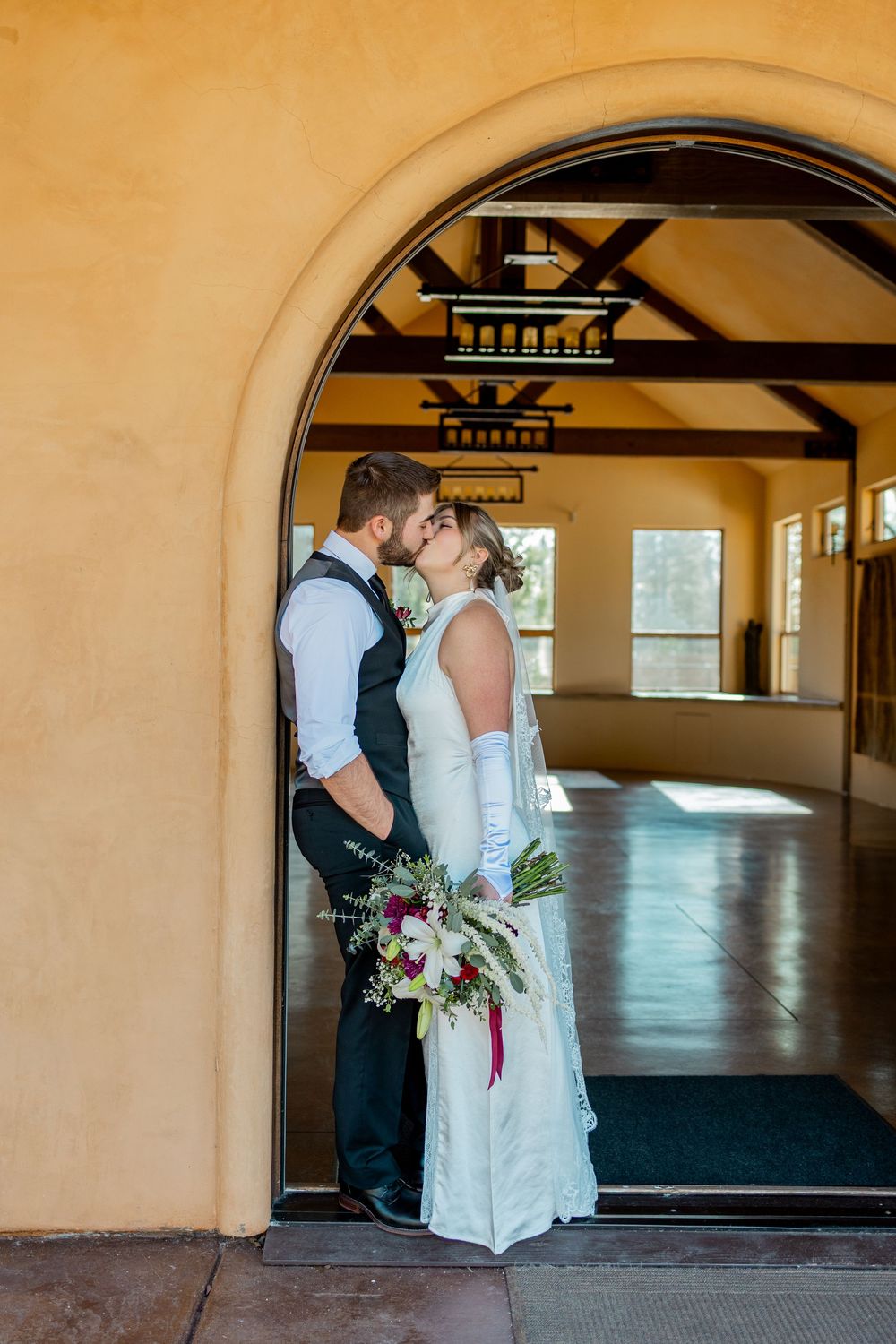 A romantic kiss silhouetted in an archway with warm lighting and architectural details creating an intimate moment.