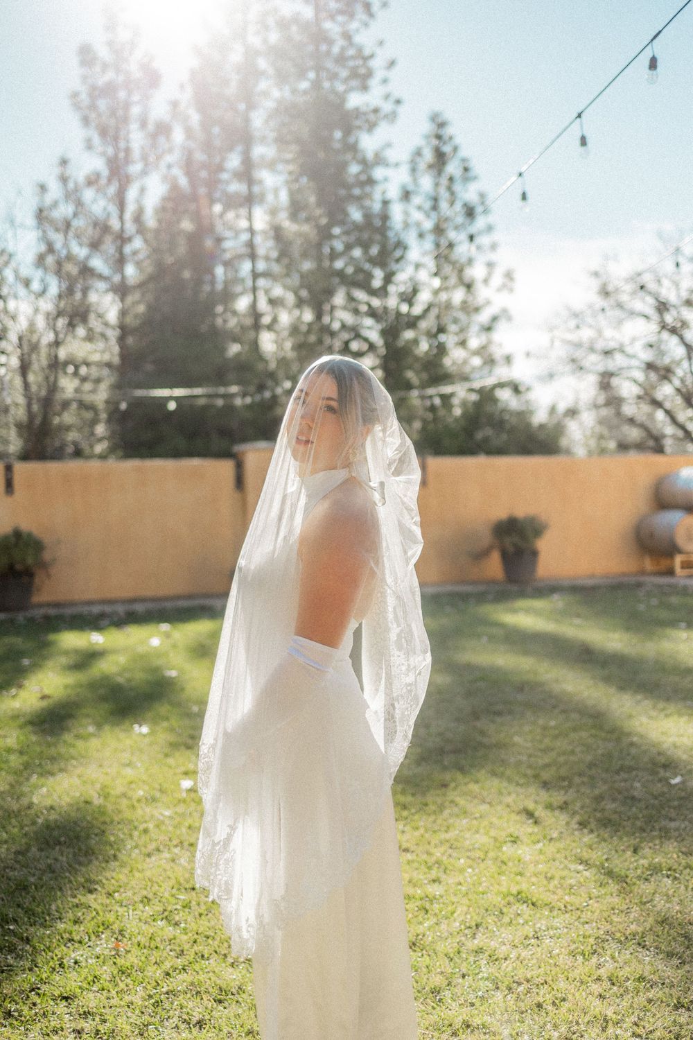 A series of dreamy backlit photos showing a bride in a flowing white wedding dress and veil in a sunlit garden.