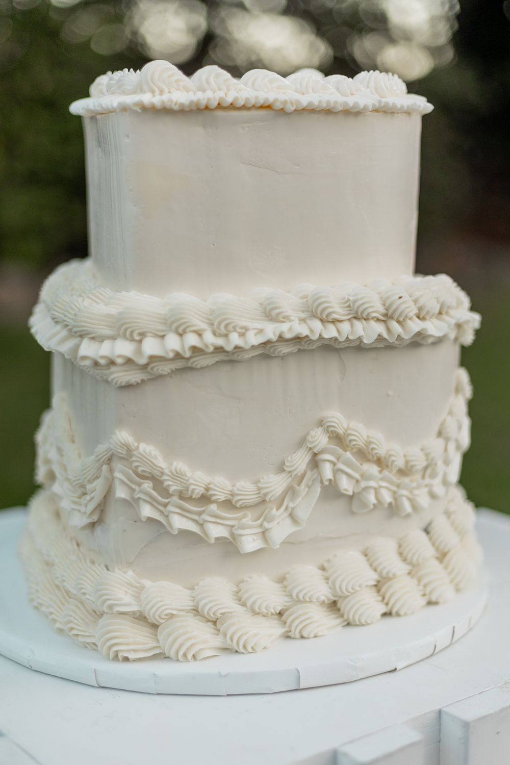 A close-up series of white wedding cake details showing elegant piped frosting ruffles and decorative patterns.
