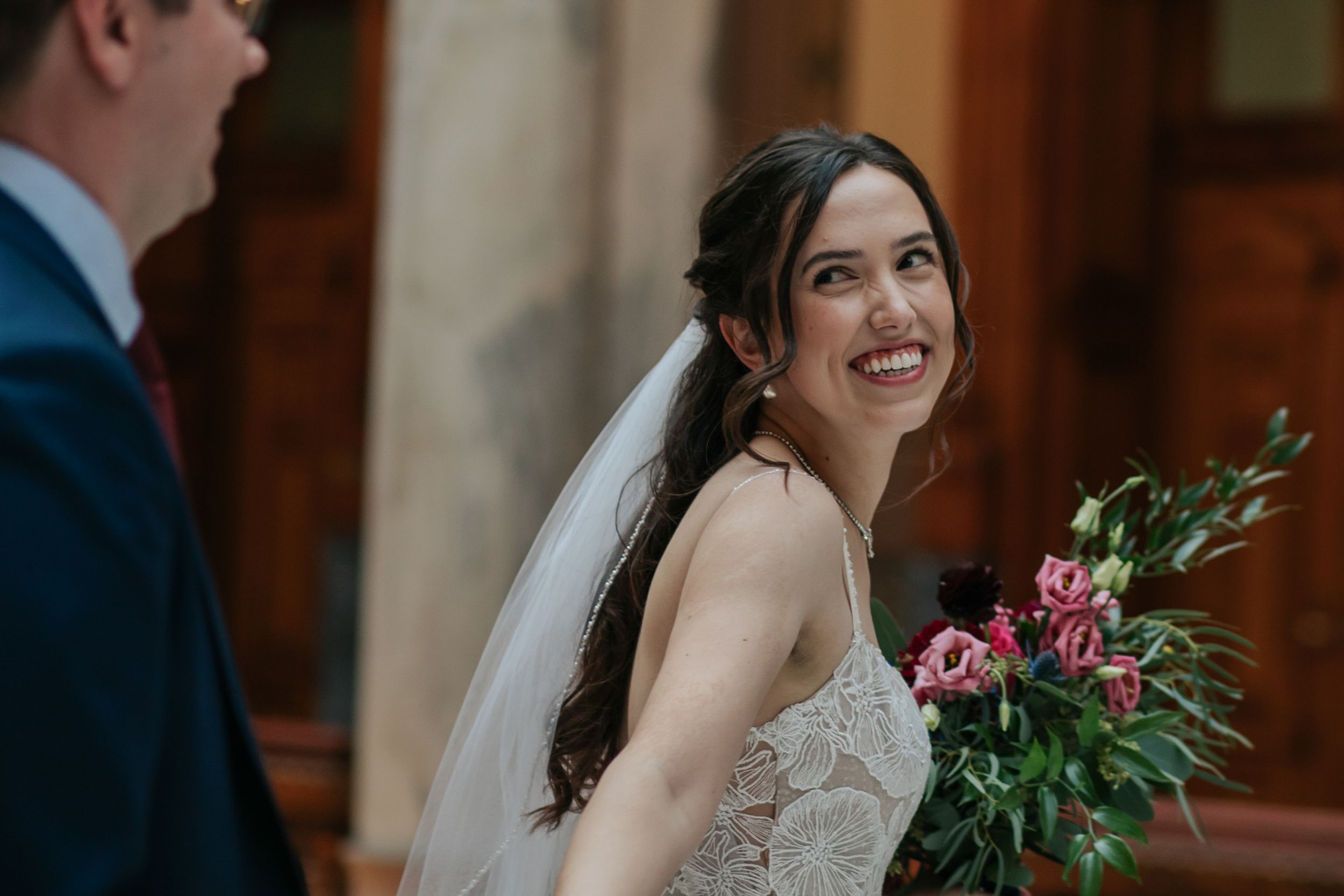 Bride and groom share a joyful moment during their wedding ceremony in an elegant indoor venue.