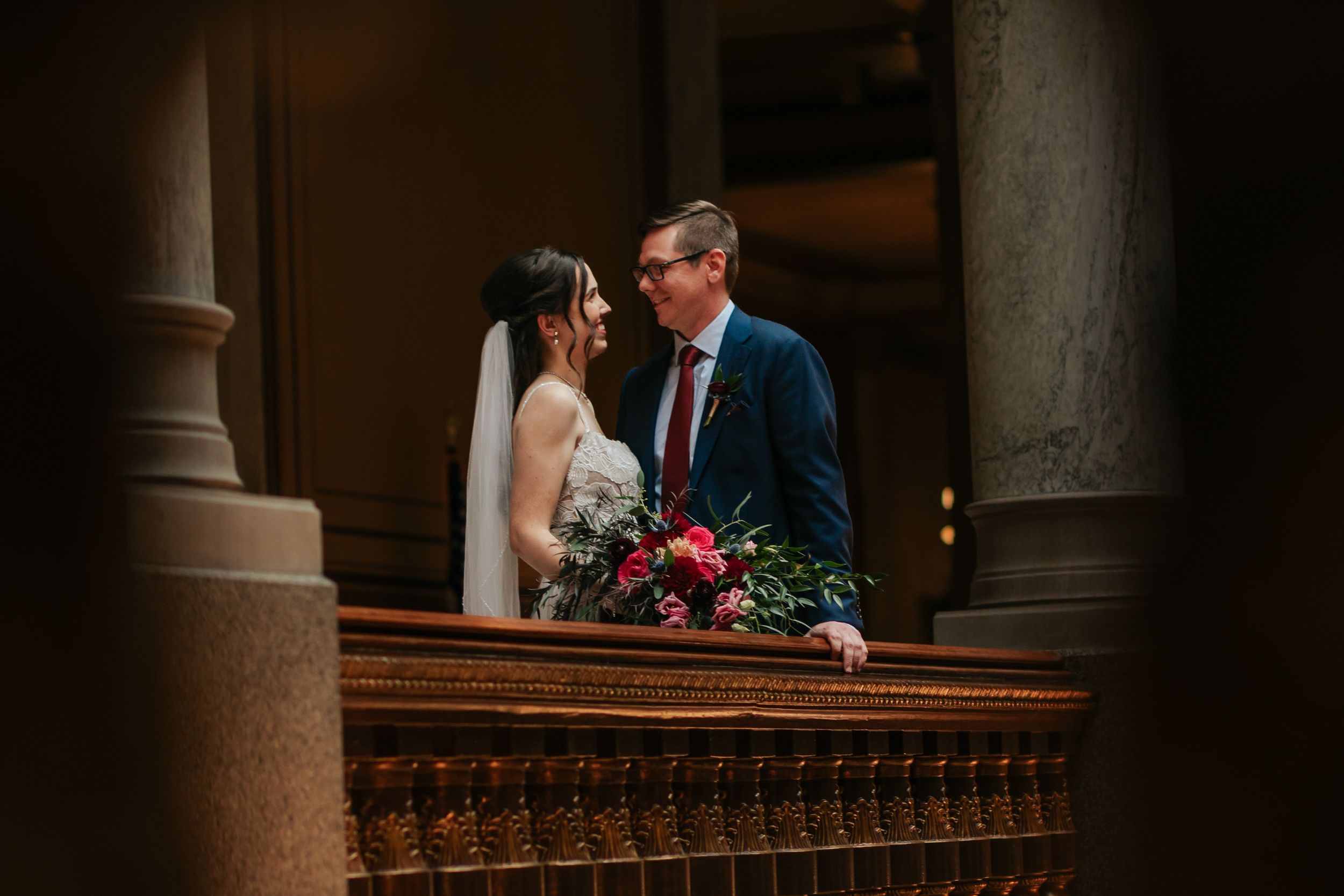 A couple shares an intimate moment in a dimly lit church interior with ornate architectural details and columns.