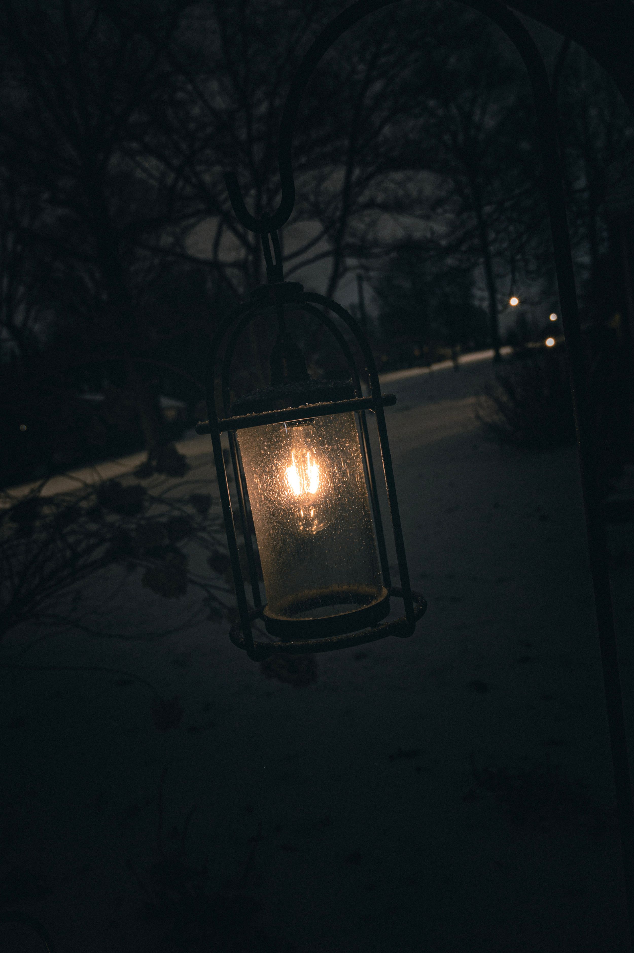 Glowing lantern casts warm light in a snowy winter scene at night.
