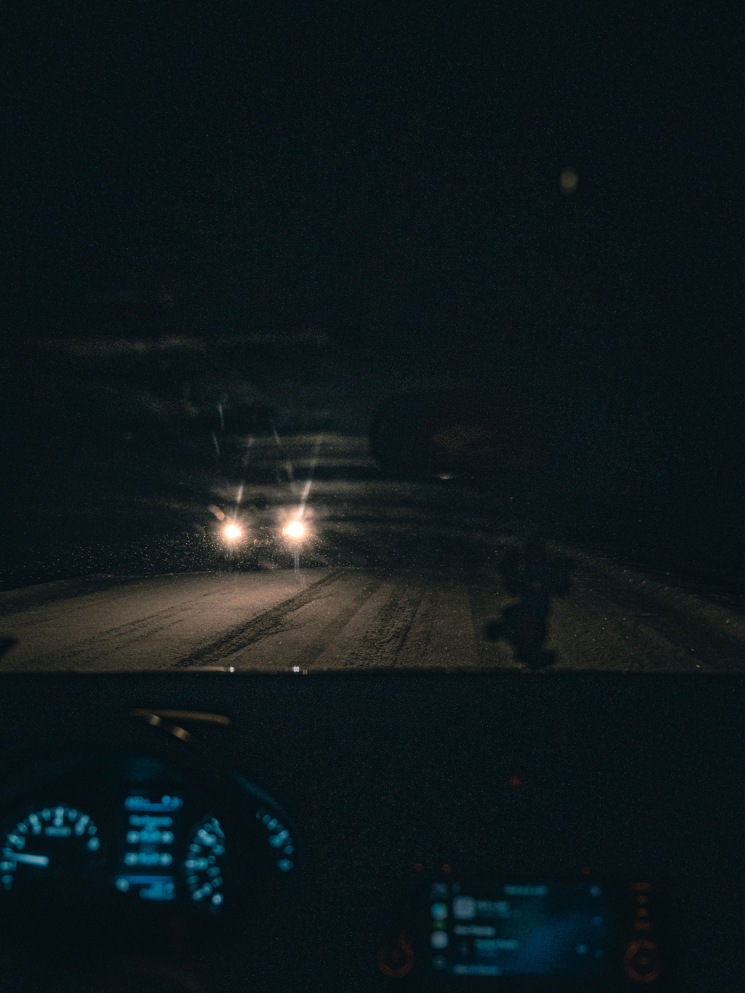 Nighttime view of illuminated road from driver's perspective with glowing dashboard.