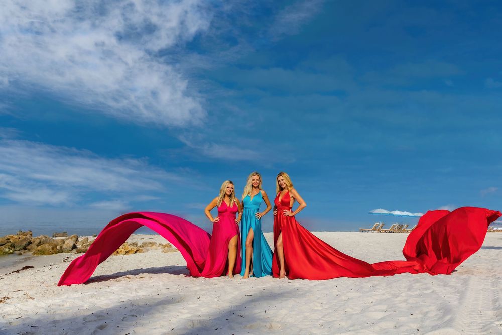 A series of flowing red fabric panels create an artistic installation against a bright blue sky and white sand beach. st Pete beach florida