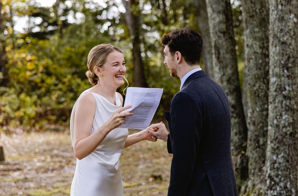 A couple shares a joyful moment exchanging vows. in a wooded outdoor setting. Weatherlow Farm wedding. Westport Massachusetts.