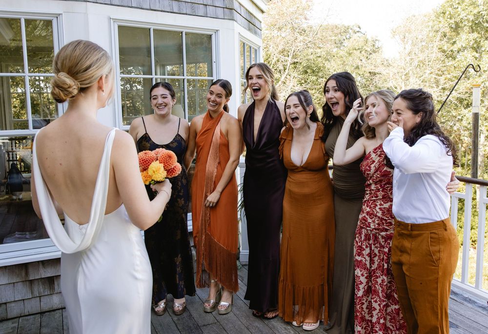 Wedding party in colorful dresses gathered on a deck for photos. Weatherlow Farm wedding. Westport Massachusetts.