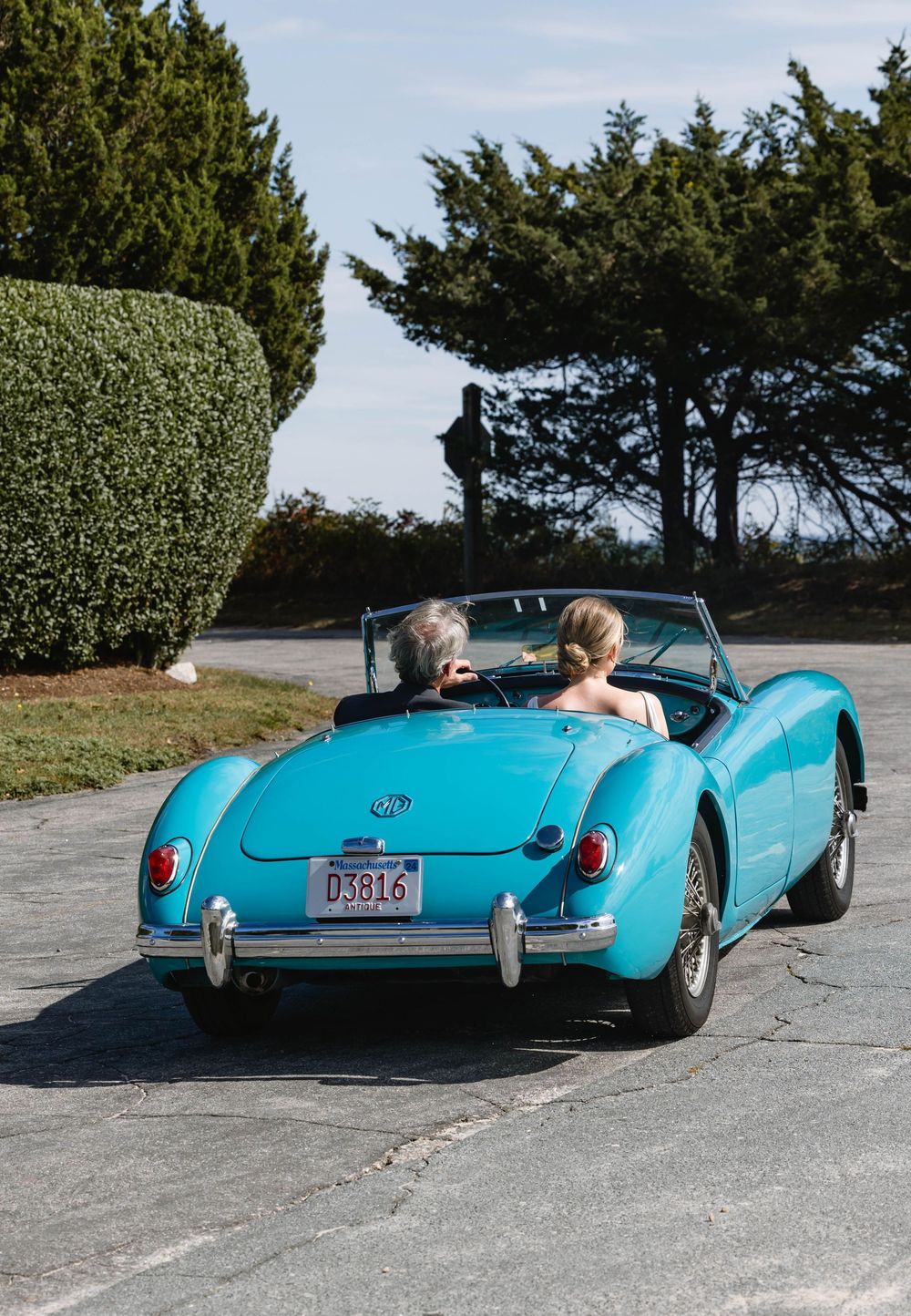 Father of the bride drives a classic turquoise convertible sports car . Weatherlow Farm wedding. Westport Massachusetts.