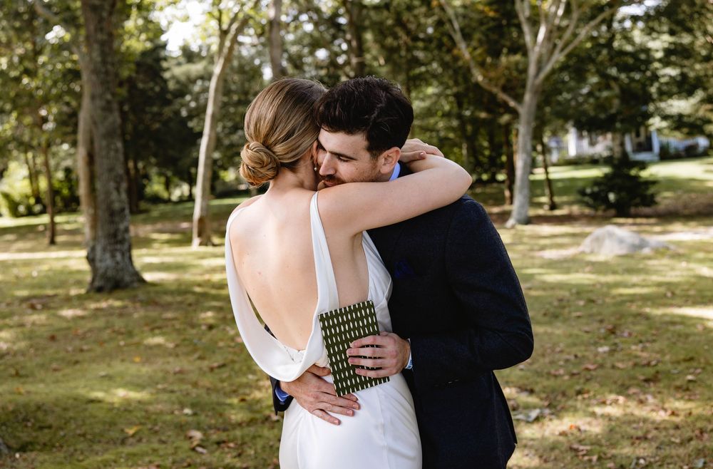 A tender embrace between a couple in wedding attire outdoors. Weatherlow Farm wedding. Westport Massachusetts.