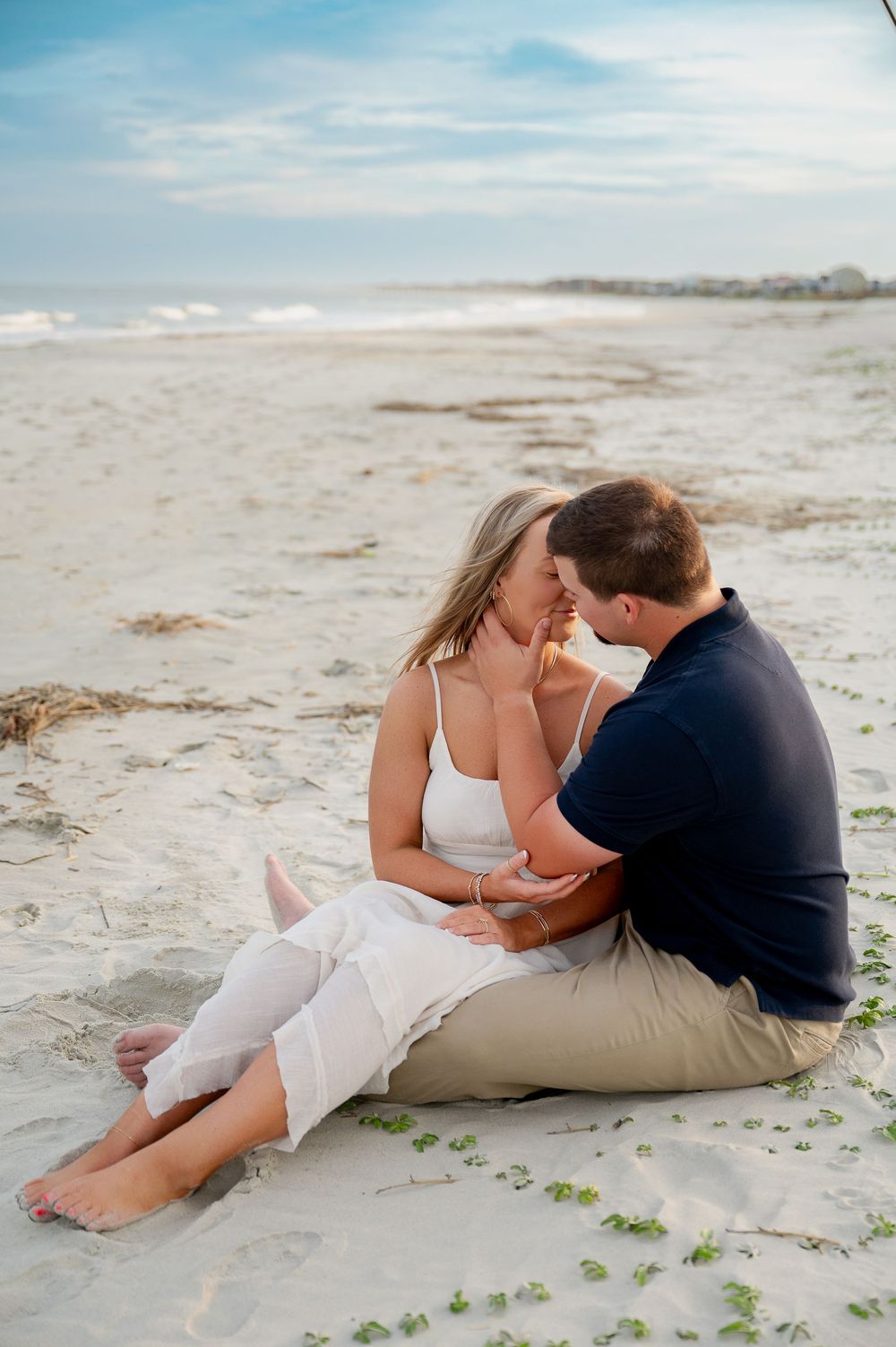 Intimate beach portraits of couple lounging on sand with ocean waves in background.