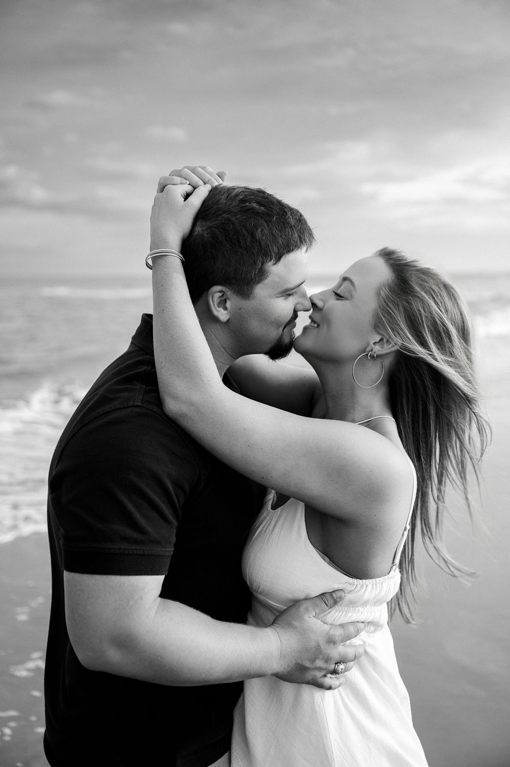 Black and white beach portraits capturing intimate moments between couple.
