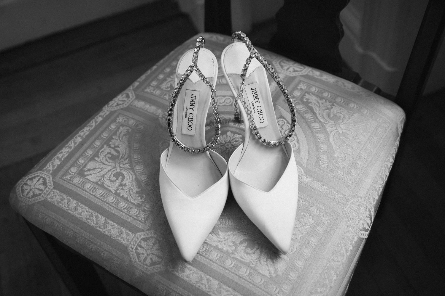 Elegant white bridal shoes displayed on a textured lace cushion.