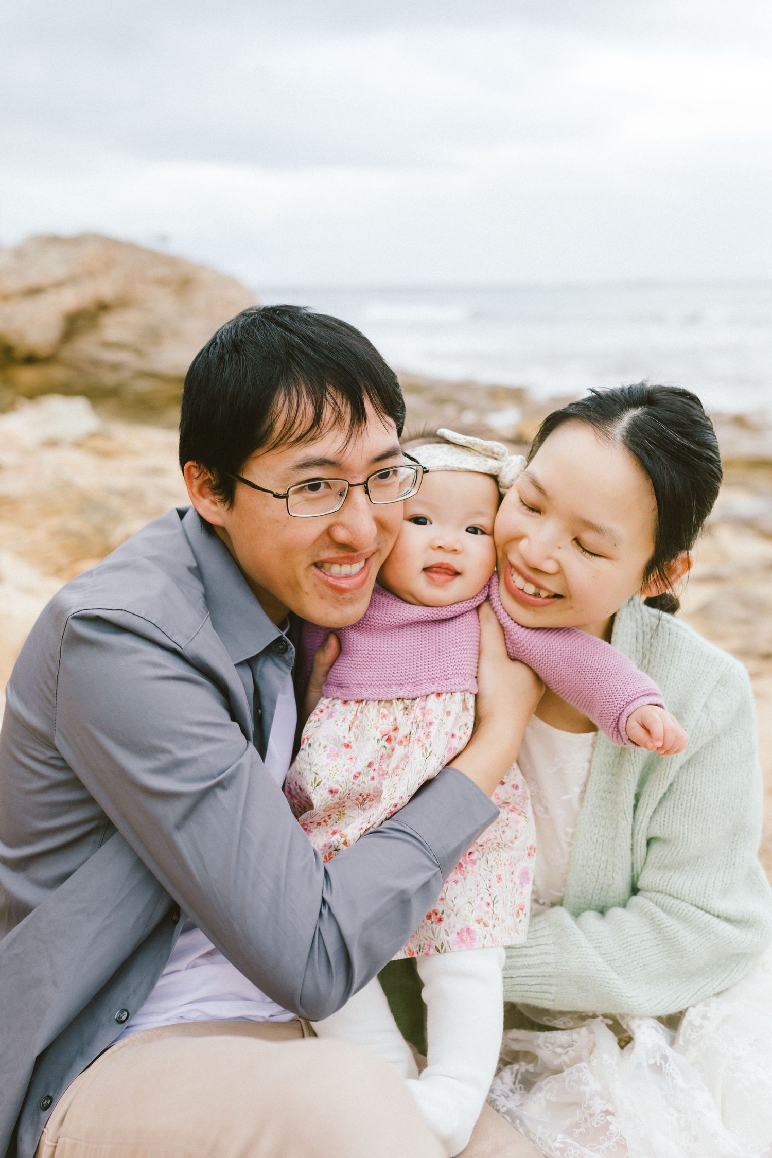 A happy family shares a joyful moment together while sitting on rocky terrain outdoors.