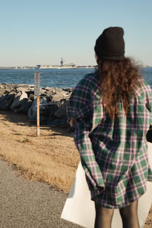A sequence of photos showing someone in a plaid shirt looking out at a rocky shoreline on a sunny day.