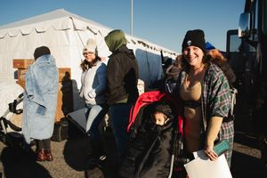 A crowd of people stand in line outside during what appears to be a winter day.