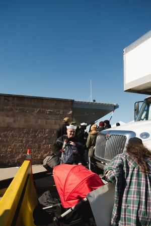Tourists gather at an observation deck against a stone wall under bright blue skies.