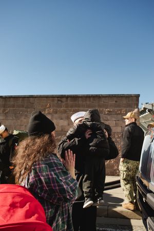 A group of people stand along a stone wall looking out at something in the distance.