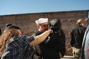 Law enforcement officers in tactical gear line up along a brick wall during a training exercise.