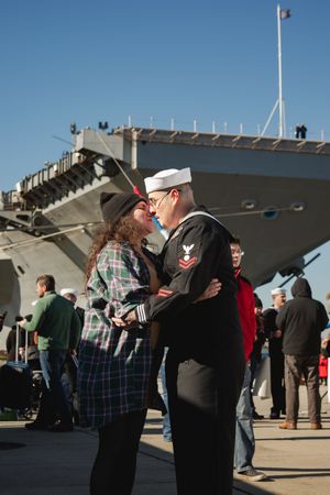 Military service members embrace loved ones during an emotional homecoming ceremony at a naval base.