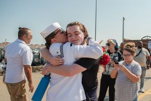 Military service members reunite with loved ones in an emotional homecoming ceremony at a naval base.