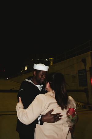 A series of photos showing a sailor and loved one embracing in an emotional reunion at night.