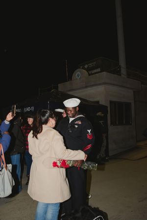 Military service members embrace during an emotional nighttime reunion ceremony.