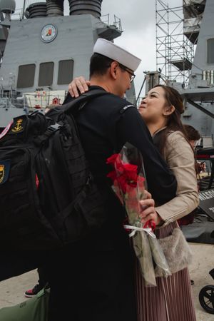 Navy sailor reunites with loved one on ship deck during emotional homecoming embrace.