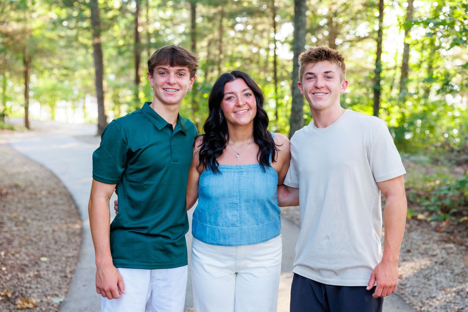 A group poses together outdoors in coordinated green and blue outfits against a wooded background on Table Rock Lake in Branson, MO.
