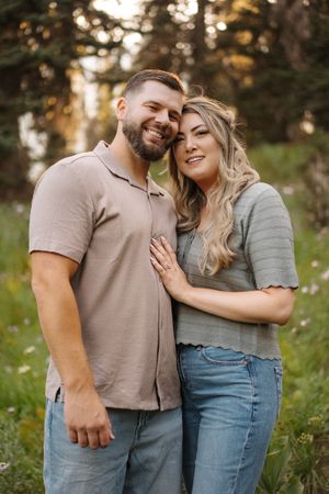 A couple shares tender moments together in a grassy outdoor setting during golden hour.