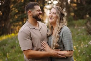 A couple shares tender moments in a sunlit meadow during an outdoor photo session at golden hour.
