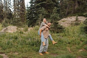 A scenic mountain meadow with evergreen trees and wildflowers in the background.