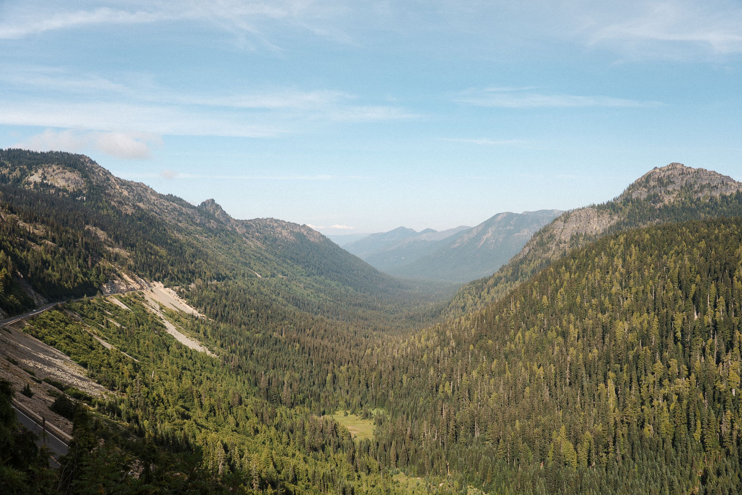 Panoramic view of lush green mountain valleys and rugged peaks in a pristine wilderness landscape.