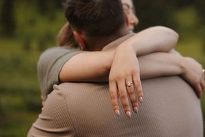 Close-up shot of hands embracing during an outdoor engagement photo session.