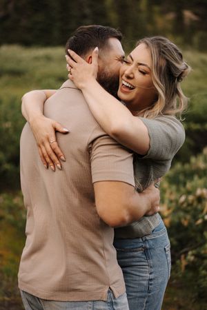 Intimate couple embraces outdoors in warm autumn light wearing casual clothing against natural greenery.
