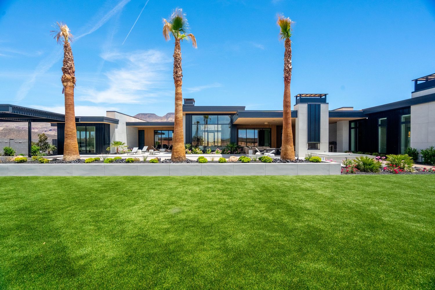 A panoramic view of a modern commercial building in St George, Ut exterior with green landscaping and blue sky.