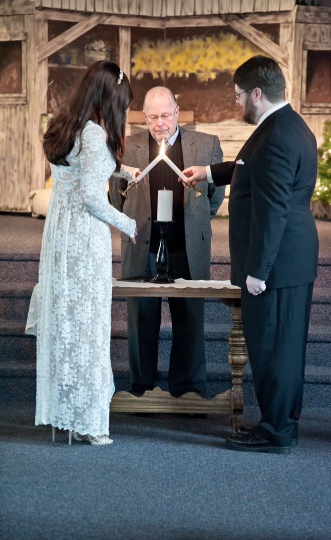 Christmas wedding in small church with bride and groom lighting unity candle