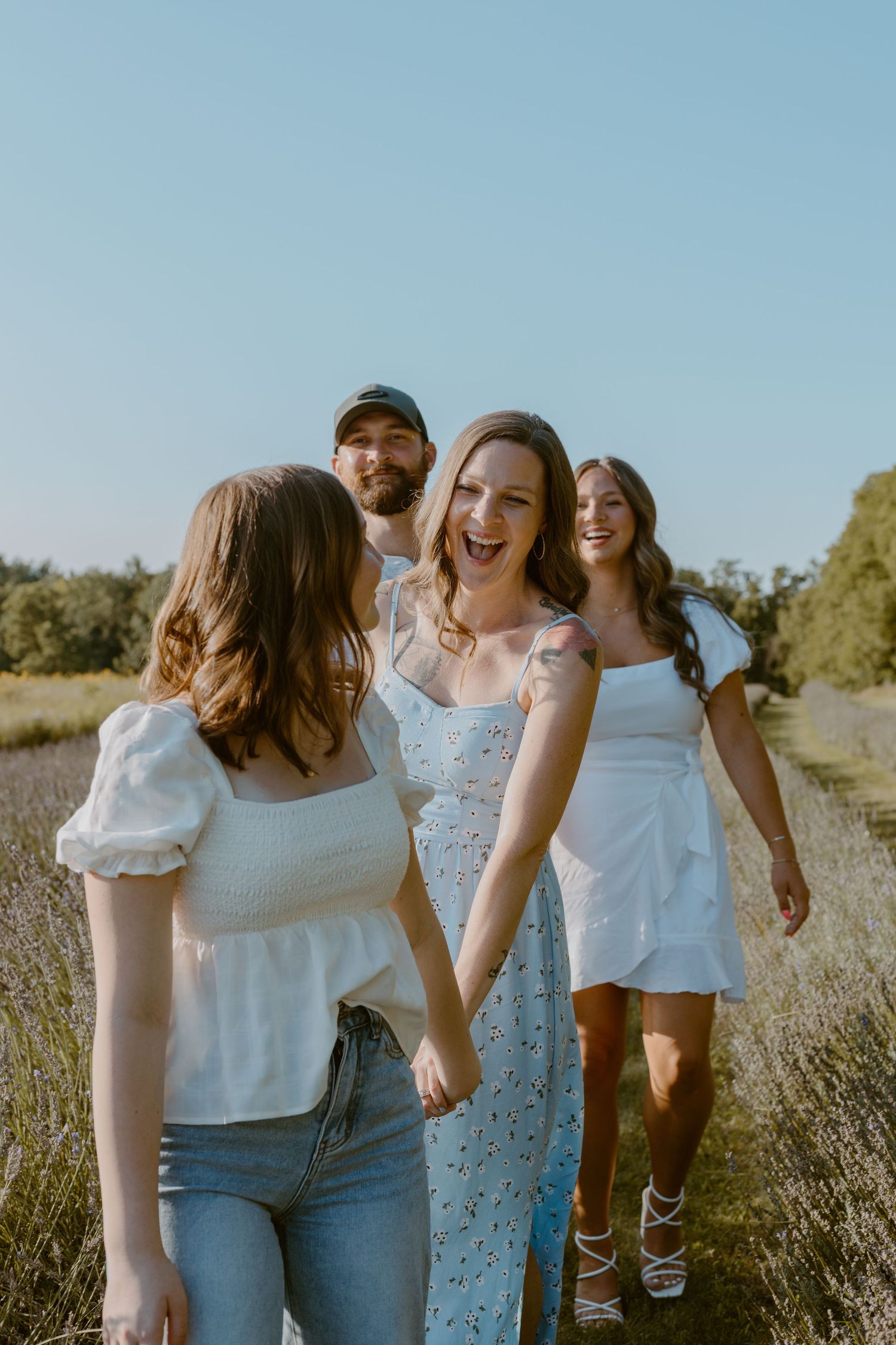A group of friends laughing together in a sunny field on a summer day.