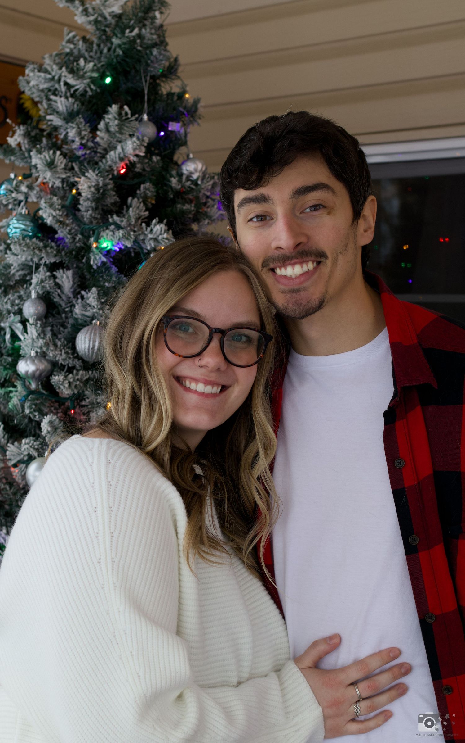 Holiday portrait in front of decorated Christmas tree with white and red winter attire.