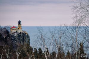 Split Rock Lighthouse stands majestically on a rocky cliff overlooking Lake Superior at dusk.