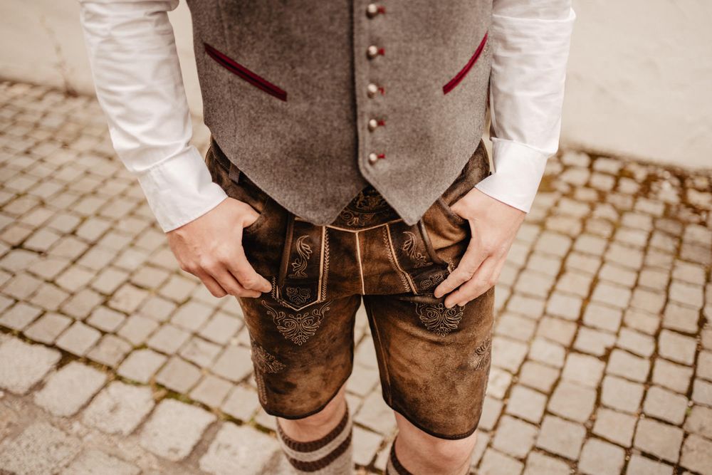 Traditional brown leather lederhosen with grey wool vest detail.
