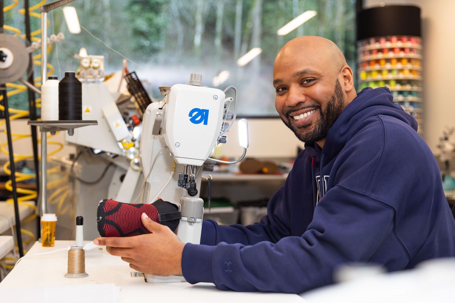 Professional seamstress working with industrial sewing machine in a bright workshop.