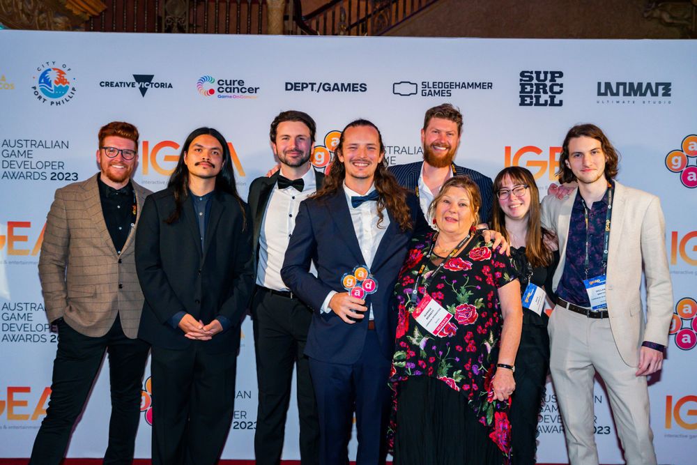 Group photo of award recipients at a formal entertainment industry event with logo backdrop.