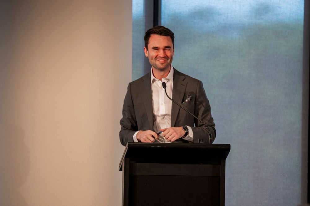 Speaker presenting at business podium in professional conference setting.